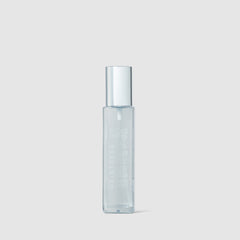 Clear glass bottle with silver cap on a light gray background