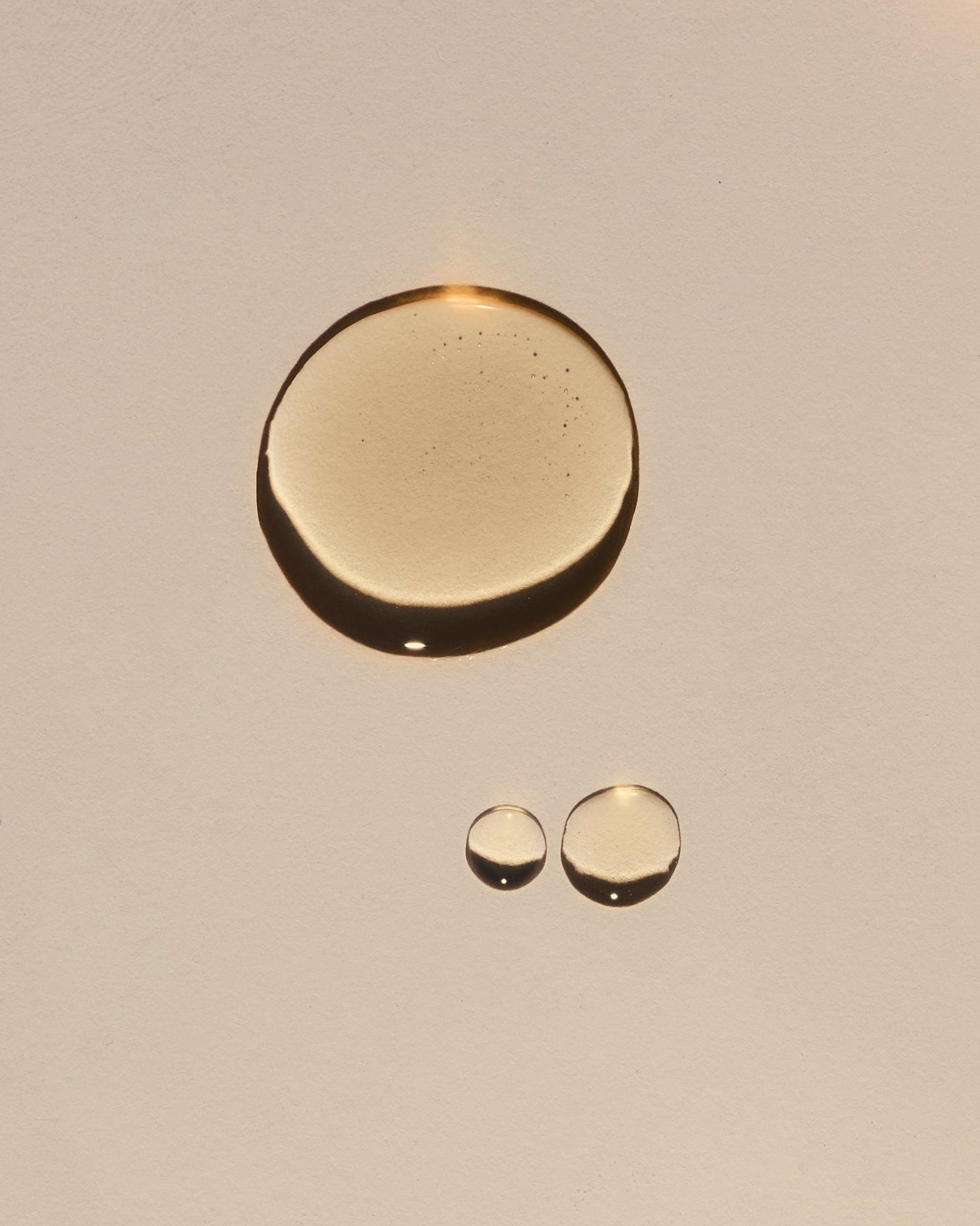 Three gold circular oil of different sizes on a beige background