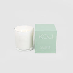 White candle with a green box labeled 'IKOU Sunrise' on a light gray background